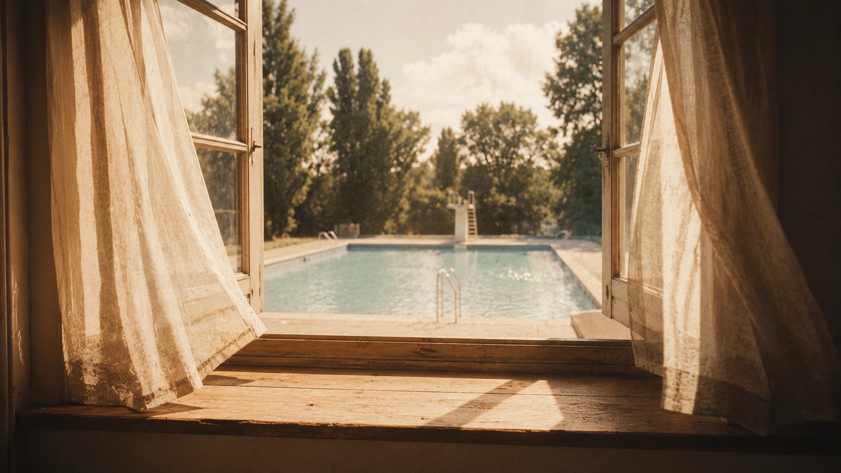 A view through an open window on a summer day, looking out to an empty, sunlit swimming pool.